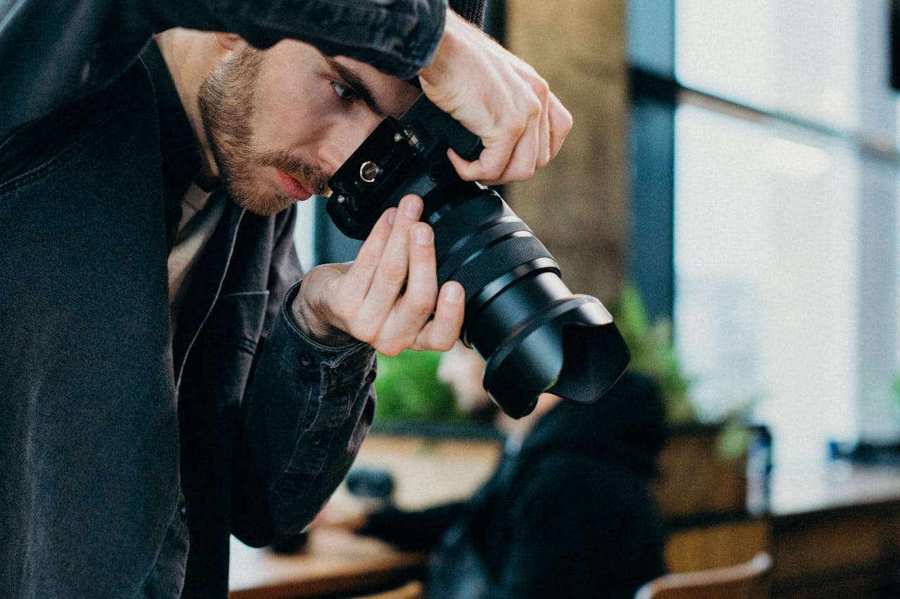 A male photographer capturing images indoors using a DSLR camera.