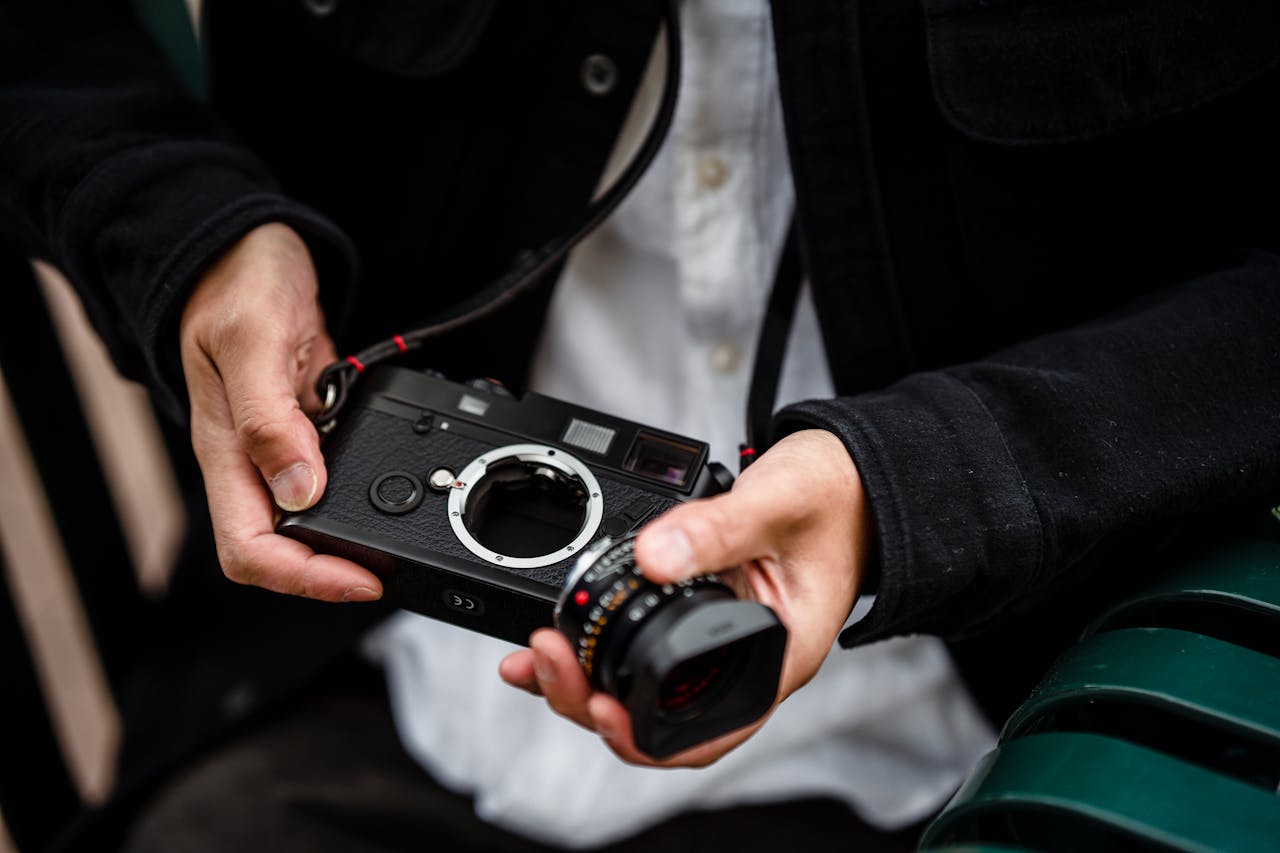 Close-up of a person handling a camera without a lens, showcasing photography gear in detail.